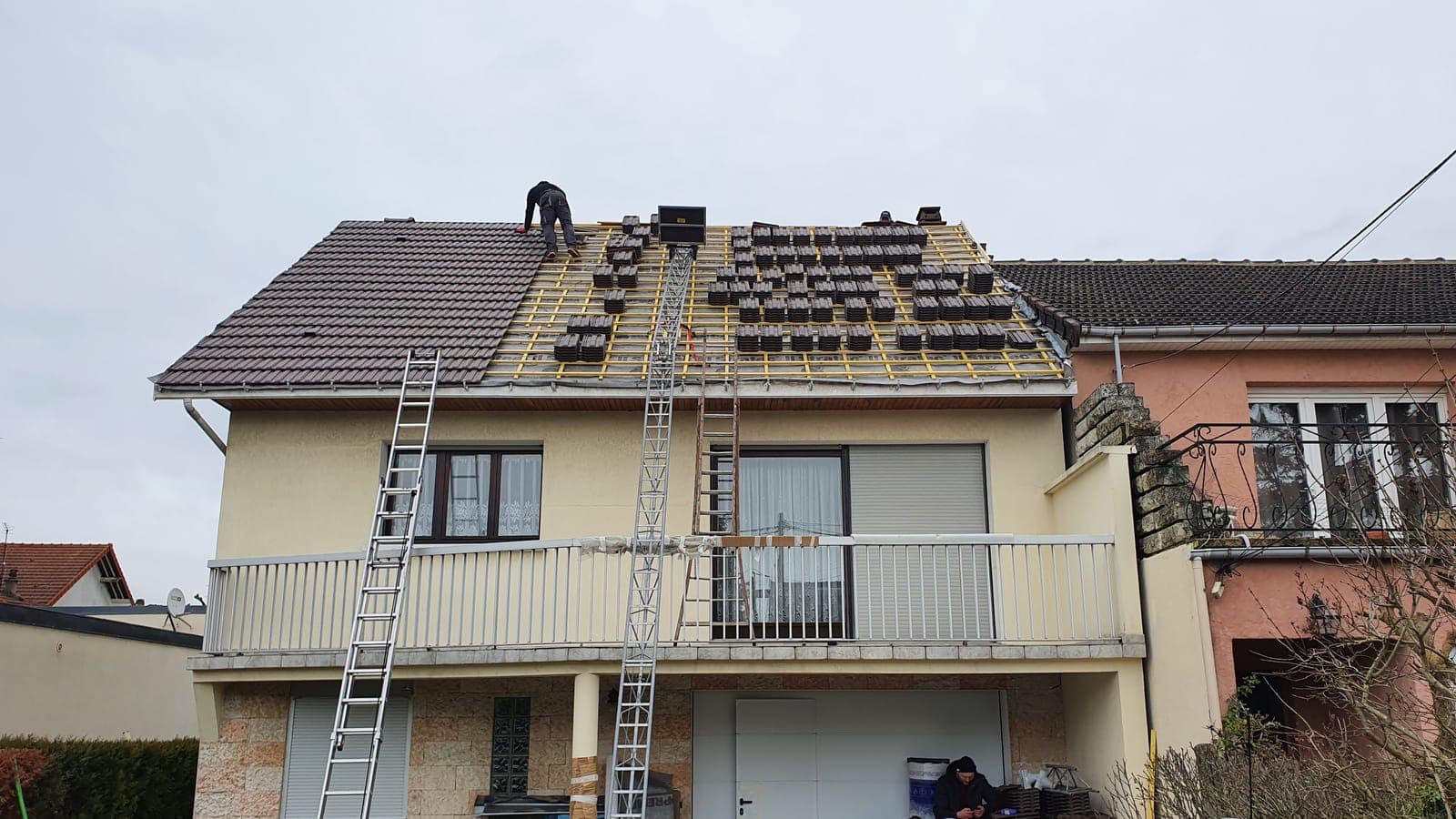 Maison à étage et balcon, couverture en tuiles reprise rang par rang, échelles contre la façade