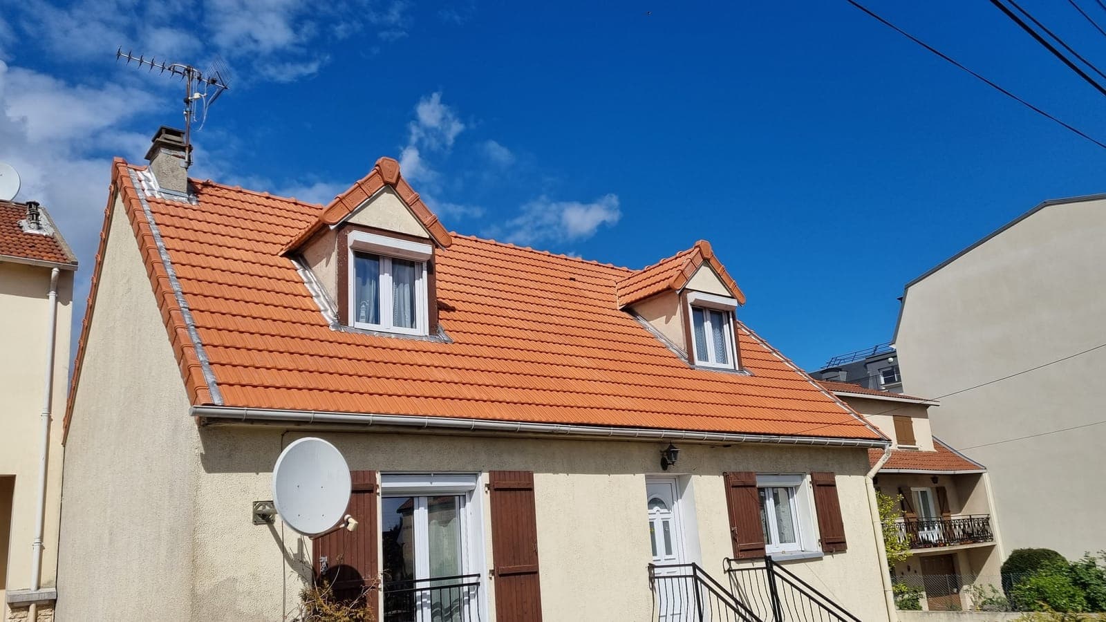 Maison à deux lucarnes sous une toiture en tuiles mécaniques orange